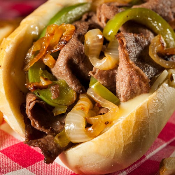 Close-up of a Lorenzo's Pizza cheesesteak with steak, melted cheese, onions, and green peppers.