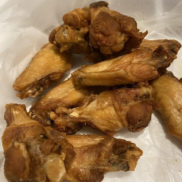 Close-up of a pile of crispy, golden-brown chicken wings from Lorenzo's Pizza, served in a white container.