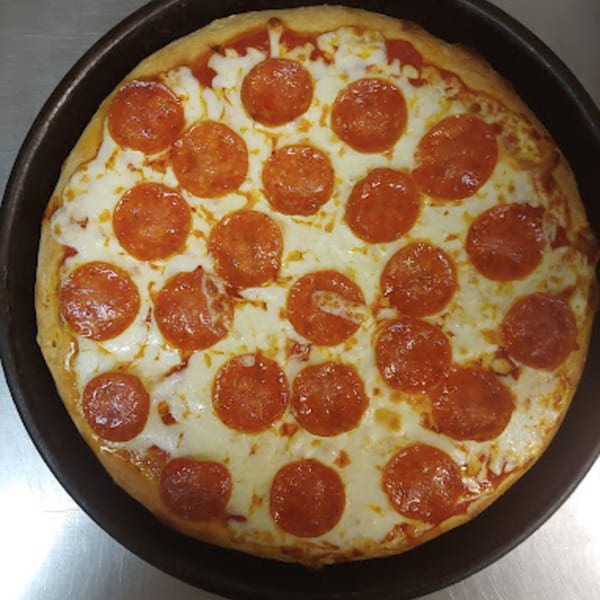 A freshly baked Lorenzo's pepperoni pizza with melted cheese and a golden crust in a dark pan.