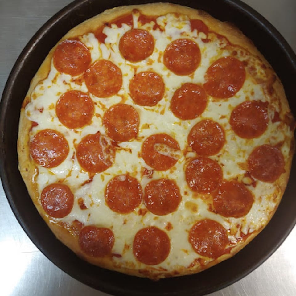 A freshly baked Lorenzo's pepperoni pizza with melted cheese and a golden crust in a dark pan.
